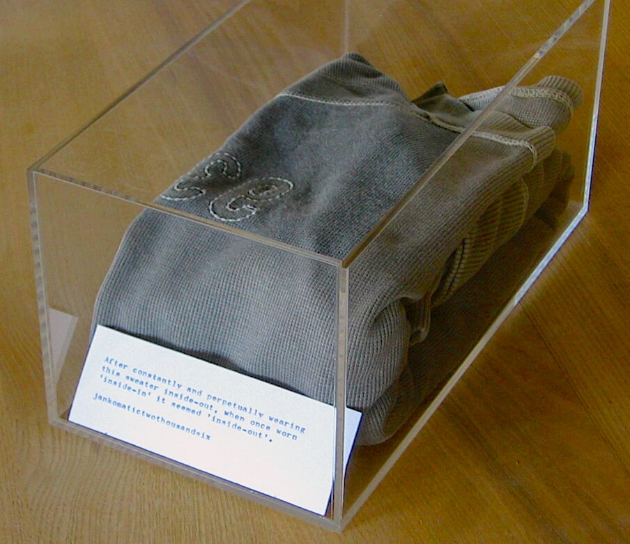 An inside out sweater placed neatly in an acrylic case