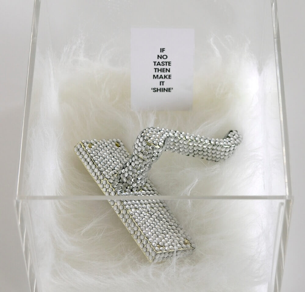 A door handle coated in fake diamonds, resting in an acrylic box
