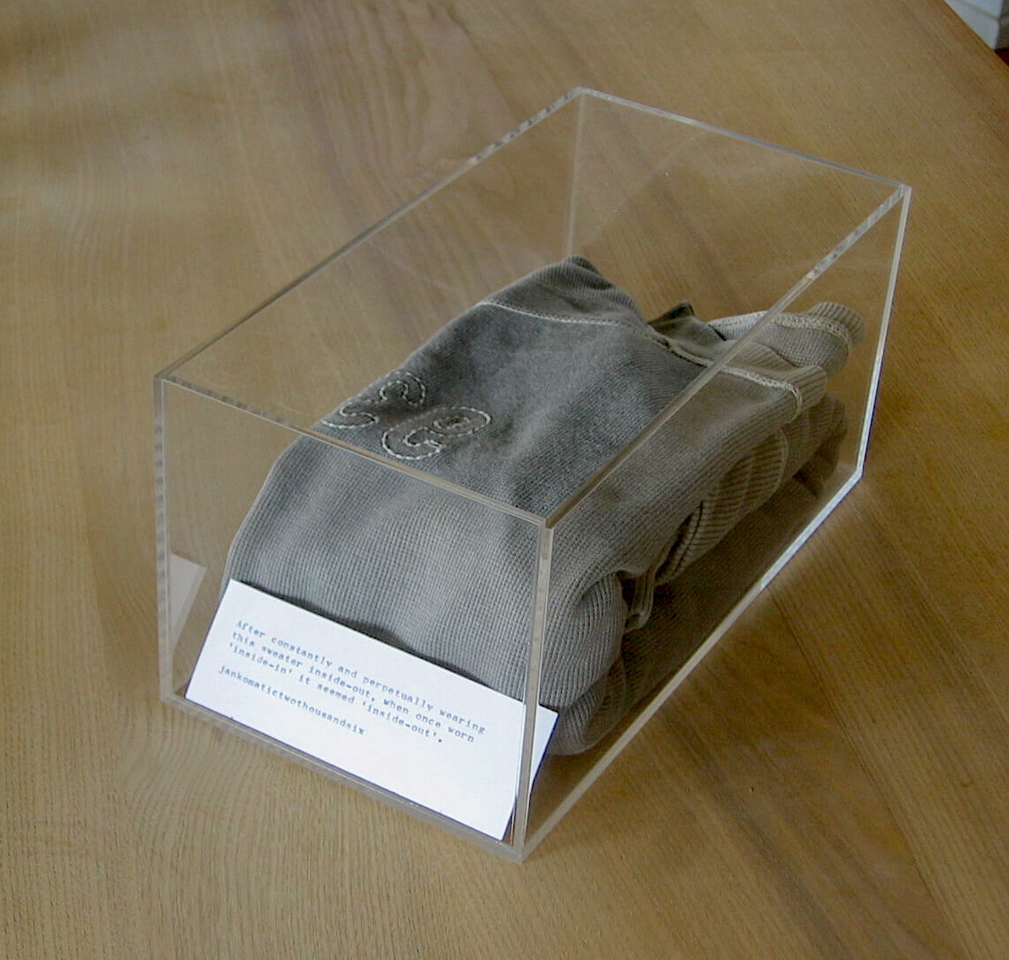 a grey sweater placed neatly into an acrylic box